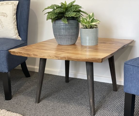 Close up photo of the small coffee table in between two blue chairs